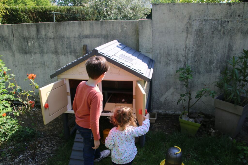 Enfants observant des poules dans leur poulailler dans un jardin familial